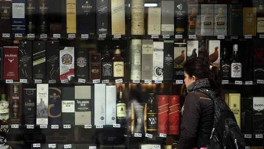 Imagen de archivo de una mujer que observa unas botellas de alcohol expuestas en una vitrina de una tienda Imagen de archivo de una mujer que observa unas botellas de alcohol expuestas en una vitrina de una tienda