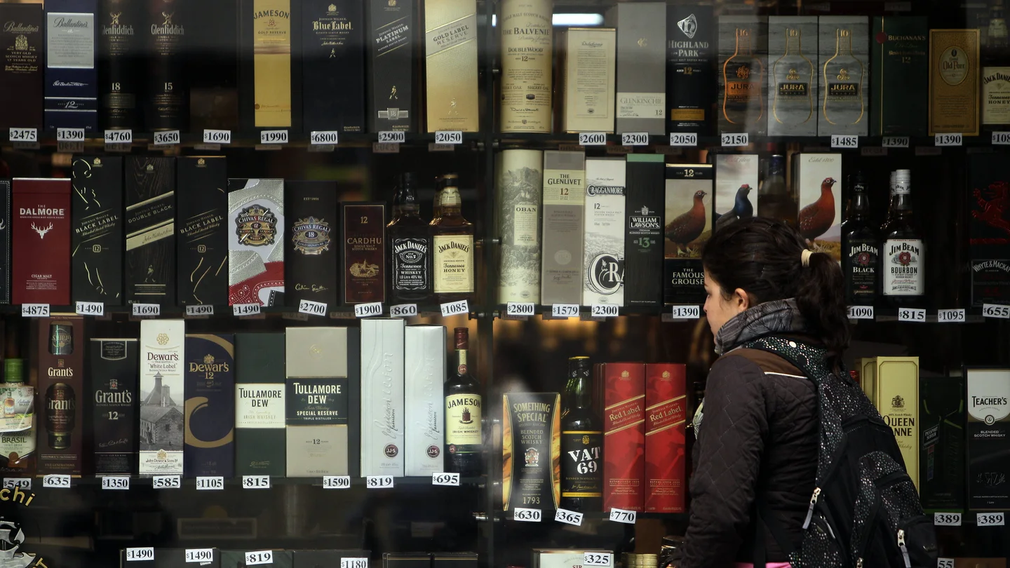 Imagen de archivo de una mujer que observa unas botellas de alcohol expuestas en una vitrina de una tienda Imagen de archivo de una mujer que observa unas botellas de alcohol expuestas en una vitrina de una tienda