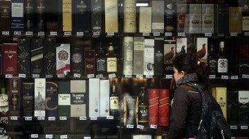 Imagen de archivo de una mujer que observa unas botellas de alcohol expuestas en una vitrina de una tienda