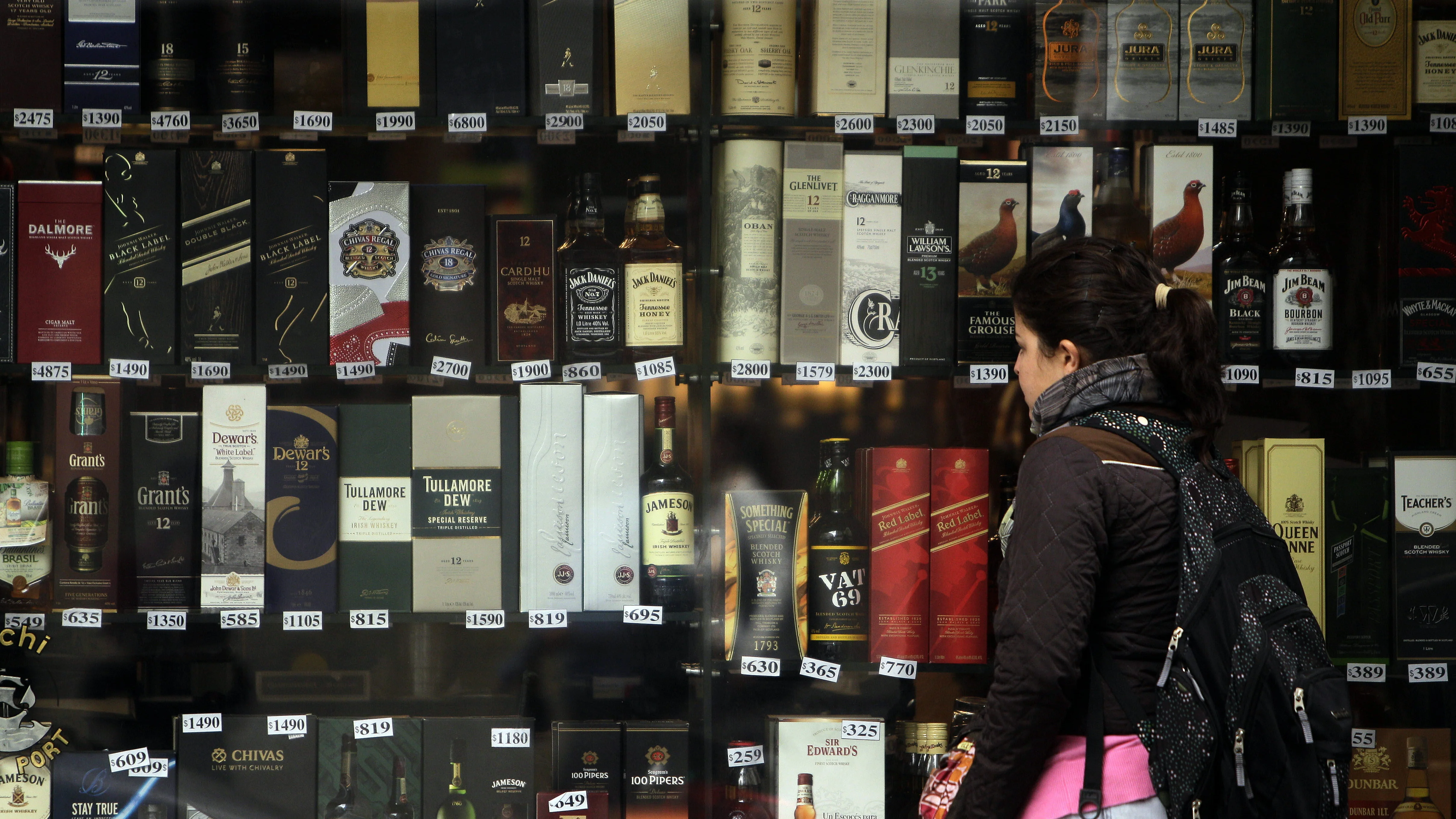 Imagen de archivo de una mujer que observa unas botellas de alcohol expuestas en una vitrina de una tienda