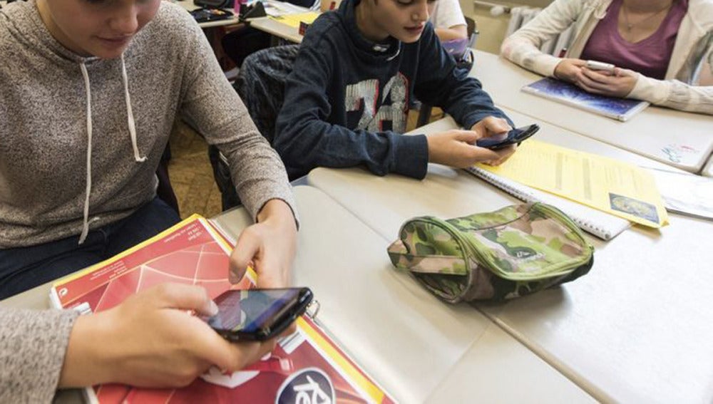 Unos alumnos utilizan el smartphone en clase