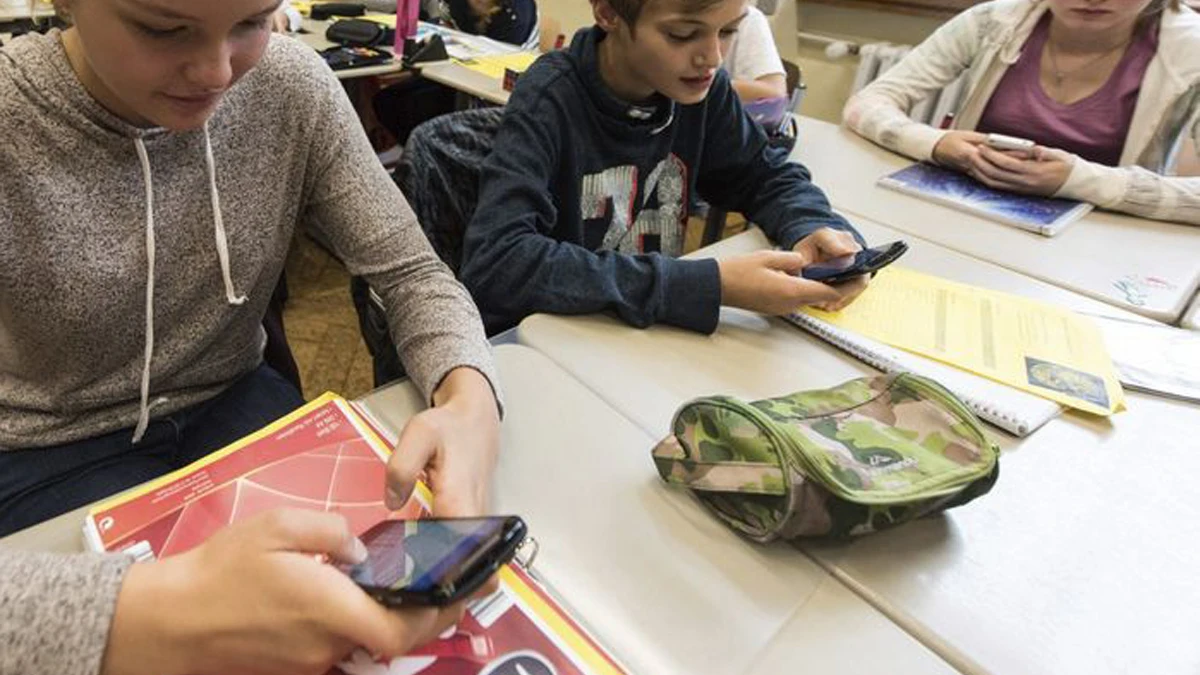 Unos alumnos utilizan el smartphone en clase