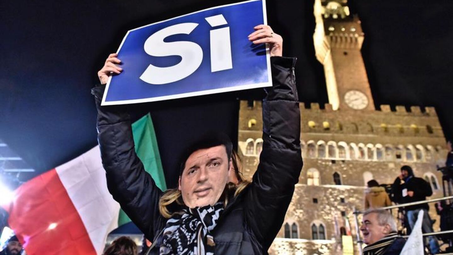  Una mujer lleva una m&aacute;scara con el rostro del primer ministro italiano Matteo Renzi y sostiene una pancarta en las que se puede leer 'S&iacute;' 