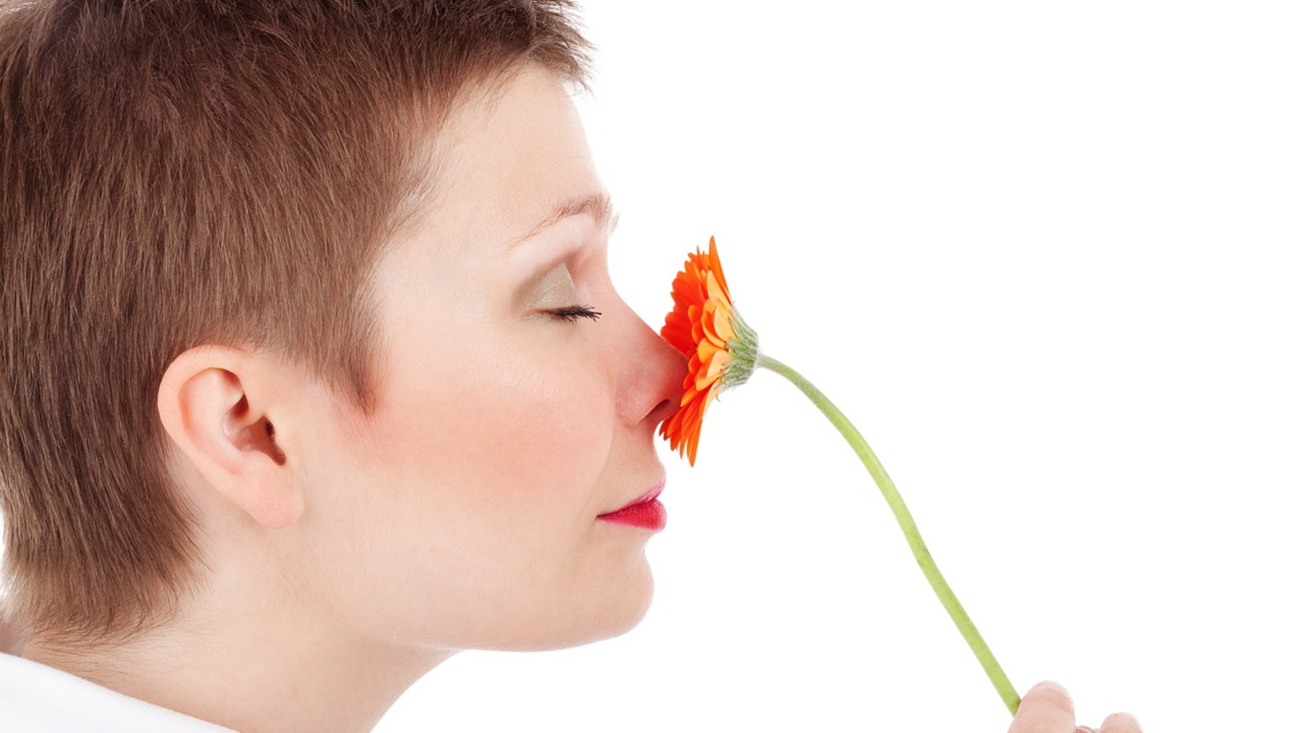 Una mujer huele una flor