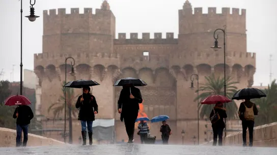 Varias personas cruzan el puente de Serranos, Valencia, bajo la lluvia Varias personas cruzan el puente de Serranos, Valencia, bajo la lluvia