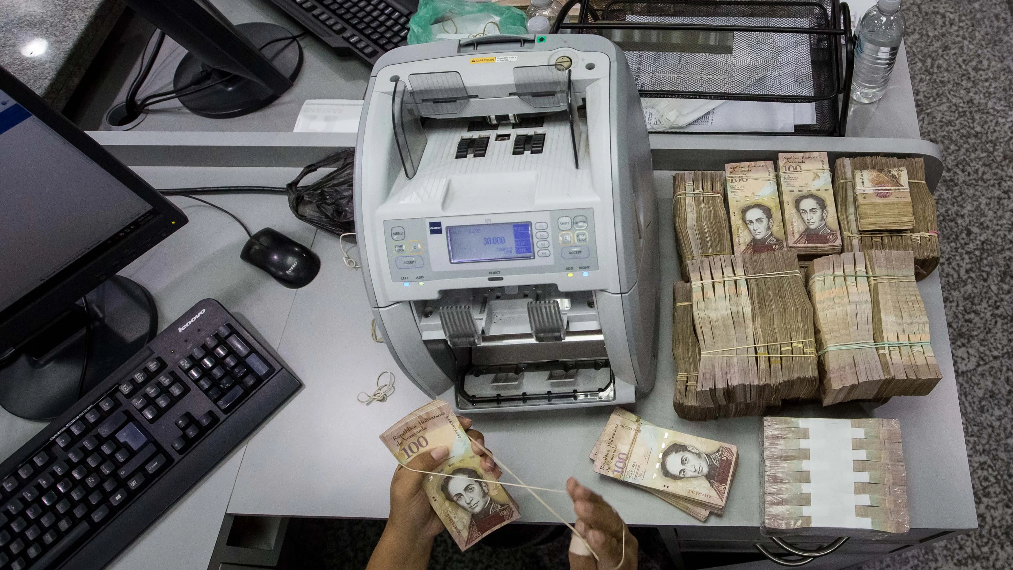 Trabajadoras de un banco cuentan billetes de 100 Bolívares en Caracas (Venezuela)