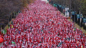 Cientos de personas vestidas de Santa Claus participan en la carrera de Papá Noel en Madrid