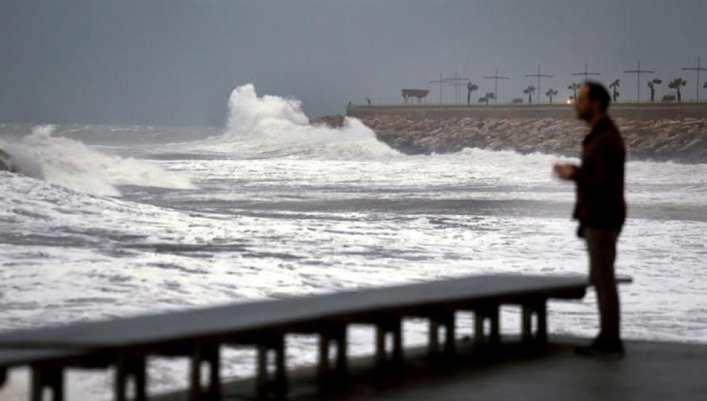 Un hombre mira como las olas rompen en las rocas del paseo marítimo de Torrevieja (Alicante), dentro del temporal de lluvia y viento en el sudeste de la Península ibérica