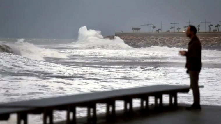 Un hombre mira como las olas rompen en las rocas del paseo marítimo de Torrevieja (Alicante), dentro del temporal de lluvia y viento en el sudeste de la Península ibérica