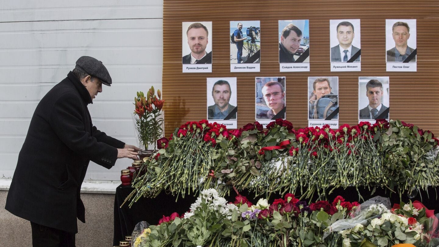 Un hombre deja flores ante los retratos de los periodistas rusos muertos en el accidente de avi&oacute;n
