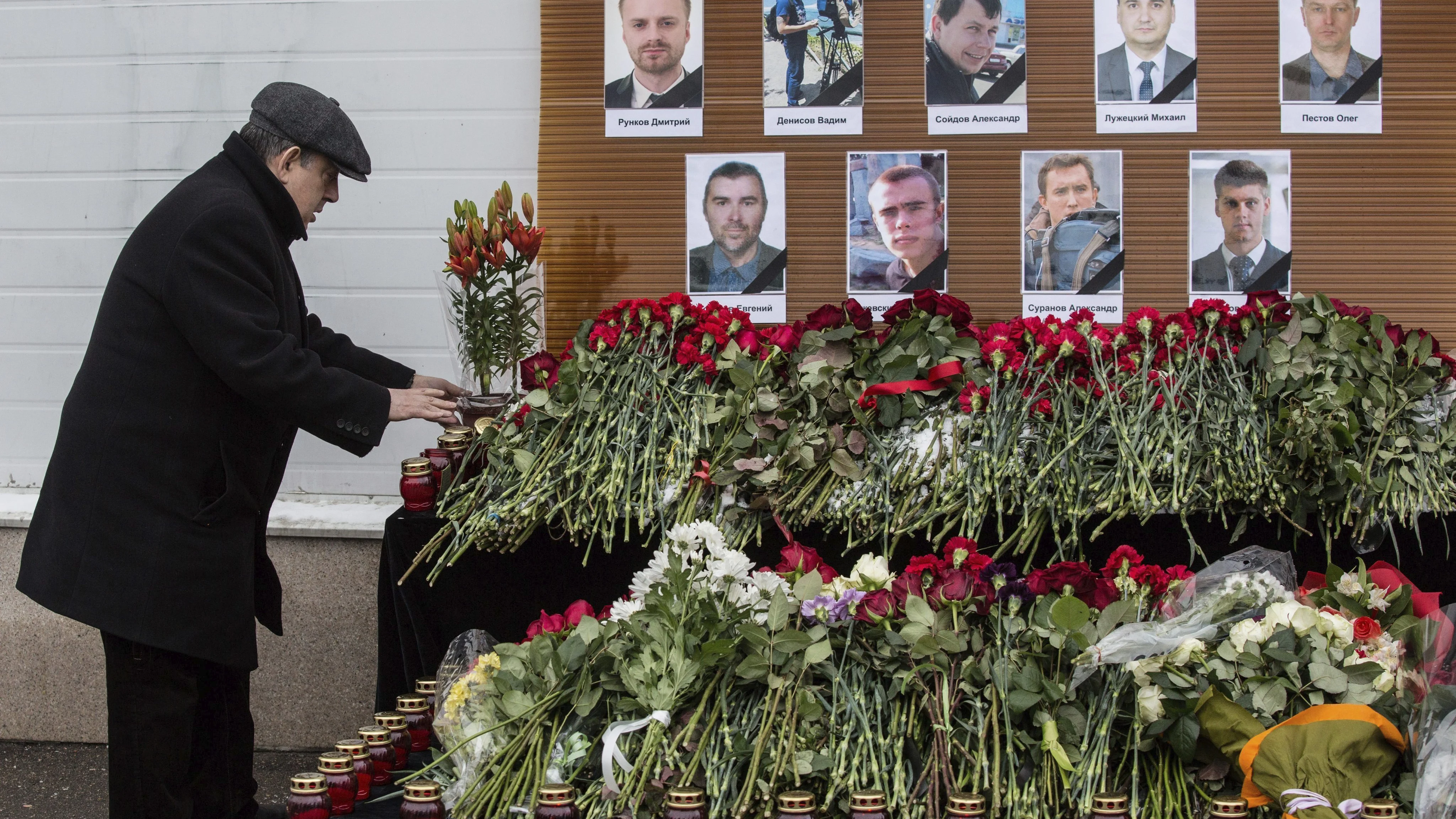 Un hombre deja flores ante los retratos de los periodistas rusos muertos en el accidente de avión