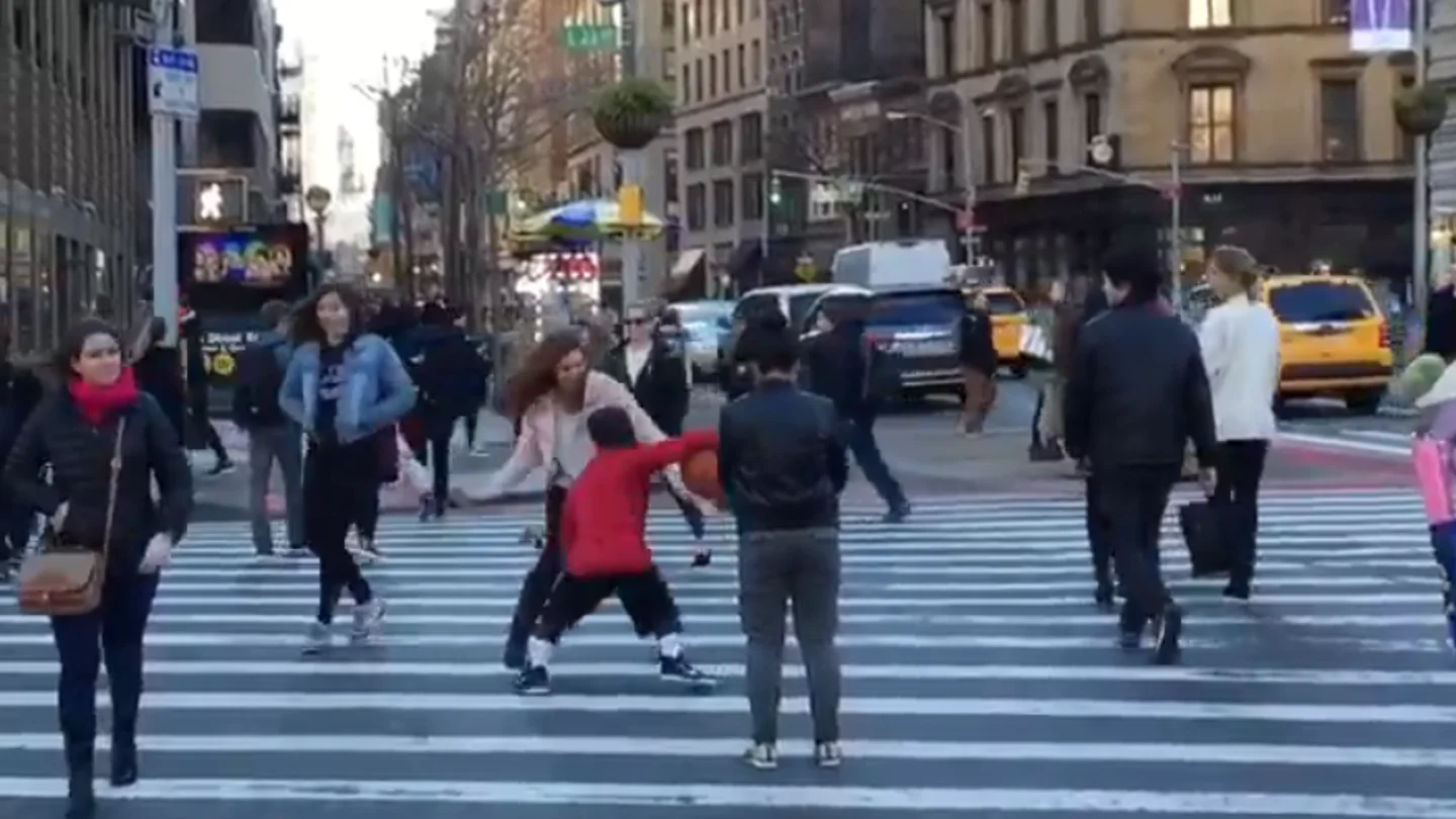 Un niño dribla a una mujer en medio de la calle Un niño dribla a una mujer en medio de la calle