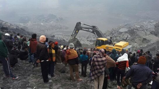 Un grupo de personas observa los trabajos de los equipos de rescate en el lugar donde se ha producido el derrumbe de una mina en el distrito de Godda en la India