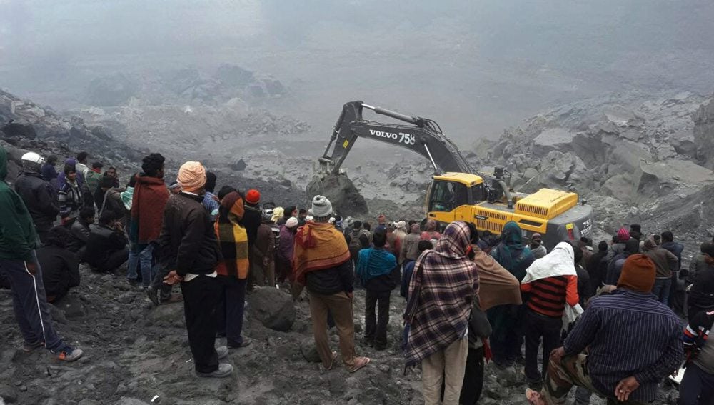 Un grupo de personas observa los trabajos de los equipos de rescate en el lugar donde se ha producido el derrumbe de una mina en el distrito de Godda en la India