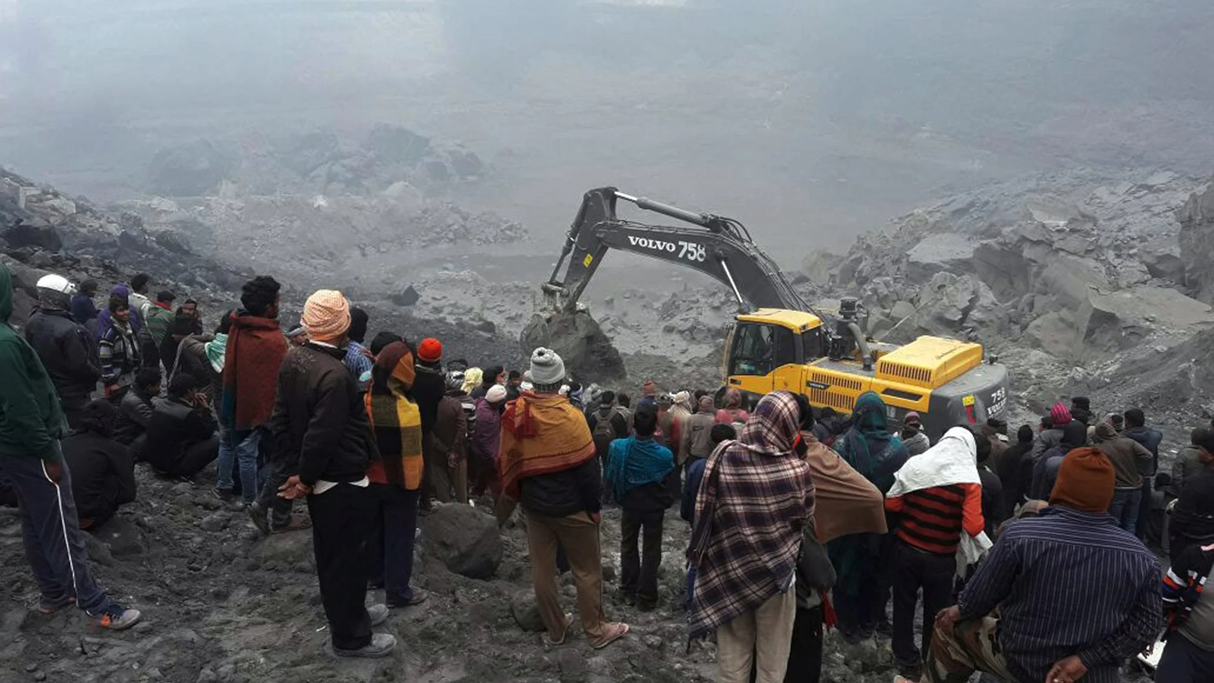 Un grupo de personas observa los trabajos de los equipos de rescate en el lugar donde se ha producido el derrumbe de una mina en el distrito de Godda en la India