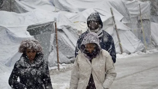 Varios refugiados caminan bajo la nieve en el campamento de refugiados de Moria Varios refugiados caminan bajo la nieve en el campamento de refugiados de Moria