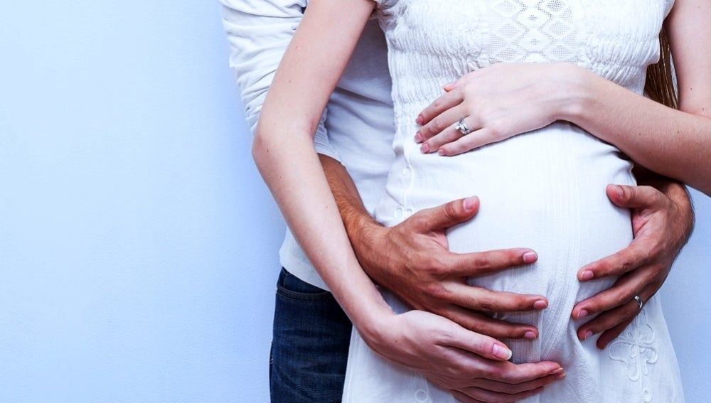 Una pareja abraza la tripa embarazada de la mujer
