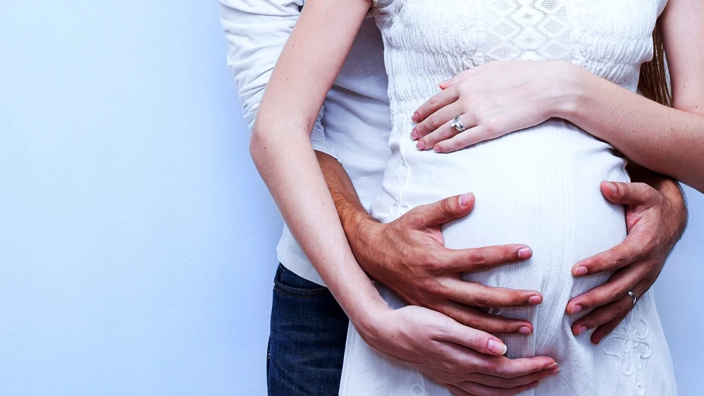Una pareja abraza la tripa embarazada de la mujer Una mujer embarazada con las manos de un hombre sobre su barriga