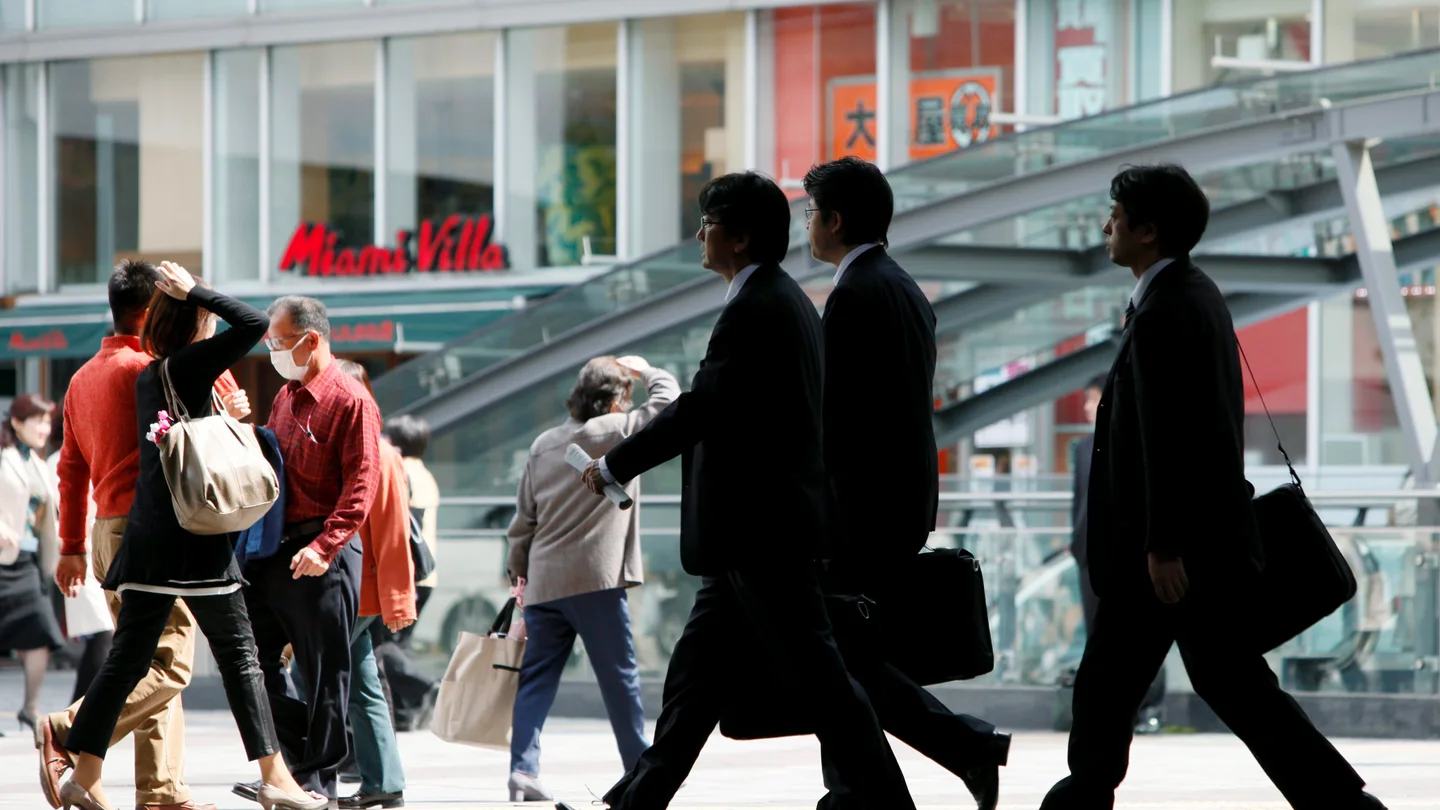 Empresarios caminan por una calle en Tokio (Japón) Empresarios caminan por una calle en Tokio (Japón)