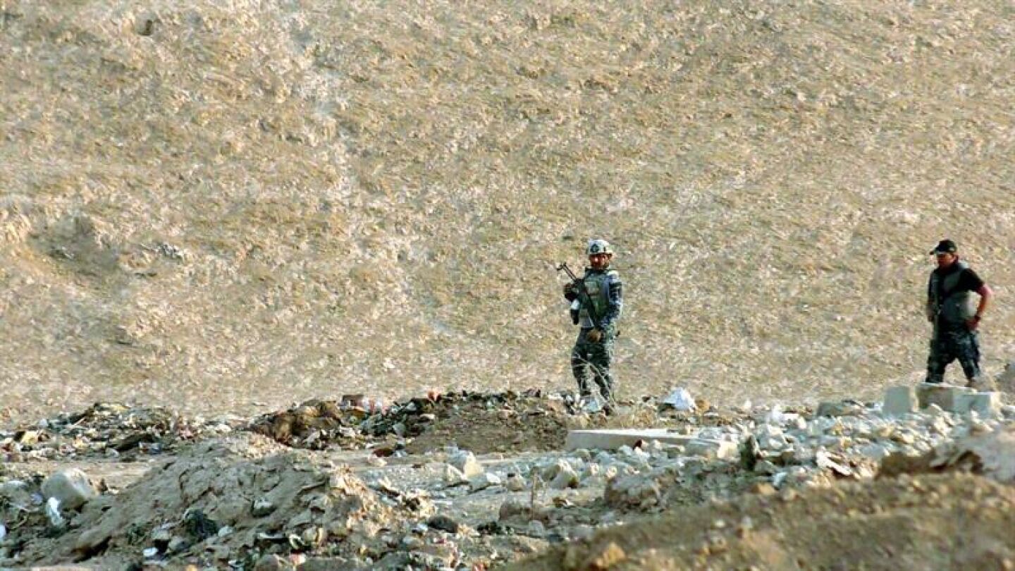 Oficiales iraqu&iacute;es inspeccionan una zona en la que fue descubierta una fosa com&uacute;n, al sur de Mosul