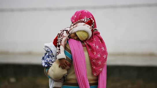 Una mujer lleva en brazos a su hijo bajo la lluvia en Srinagar (India) Una mujer lleva en brazos a su hijo bajo la lluvia en Srinagar (India)