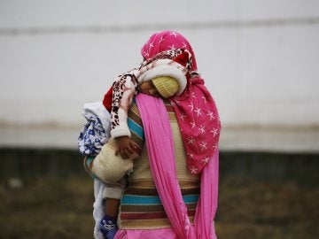 Una mujer lleva en brazos a su hijo bajo la lluvia en Srinagar (India) Una mujer lleva en brazos a su hijo bajo la lluvia en Srinagar (India)