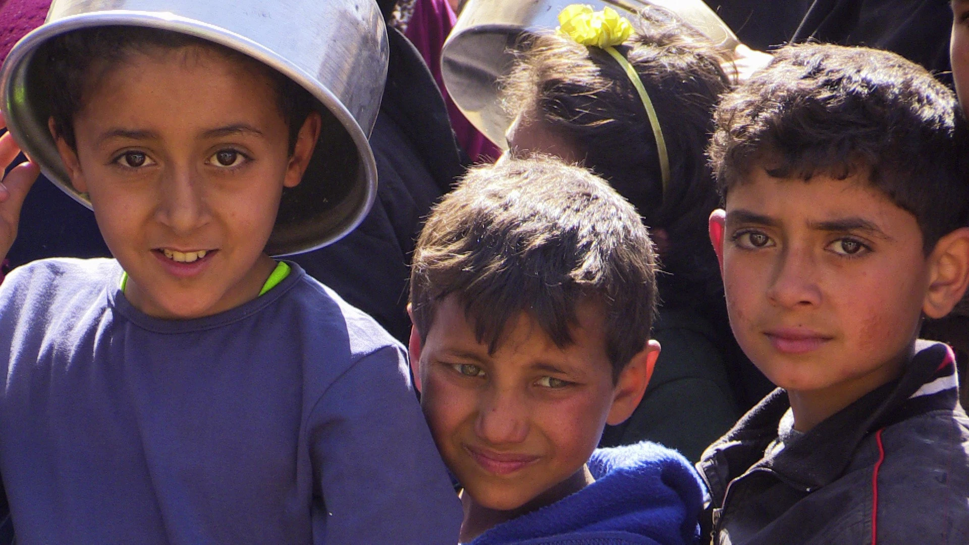 Unos niños del campamento de desplazados de Yibrin, en Alepo, hacen cola para recoger comida.