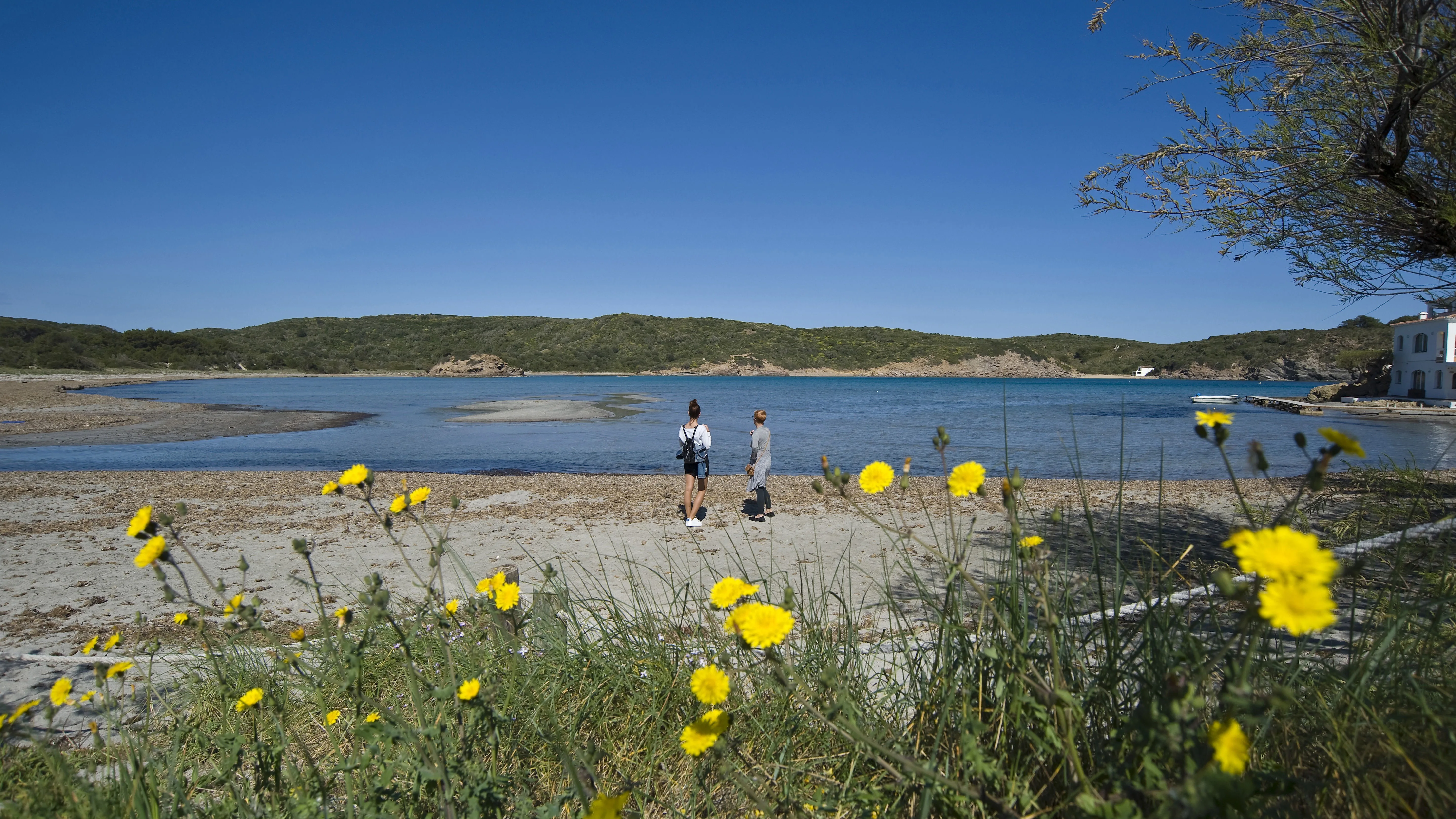 Dos personas caminan por la playa del Parque Natural de Es Grau