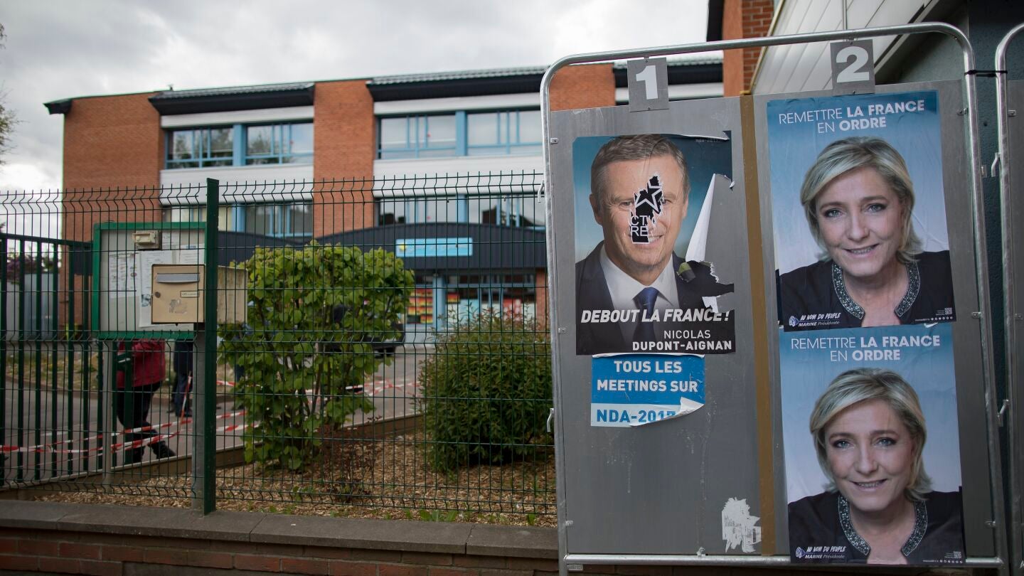 Carteles con alguno de los candidatos presidenciales en Francia adornan vallas publicitarias en el exterior de una mesa electoral en Par&iacute;s (Francia)
