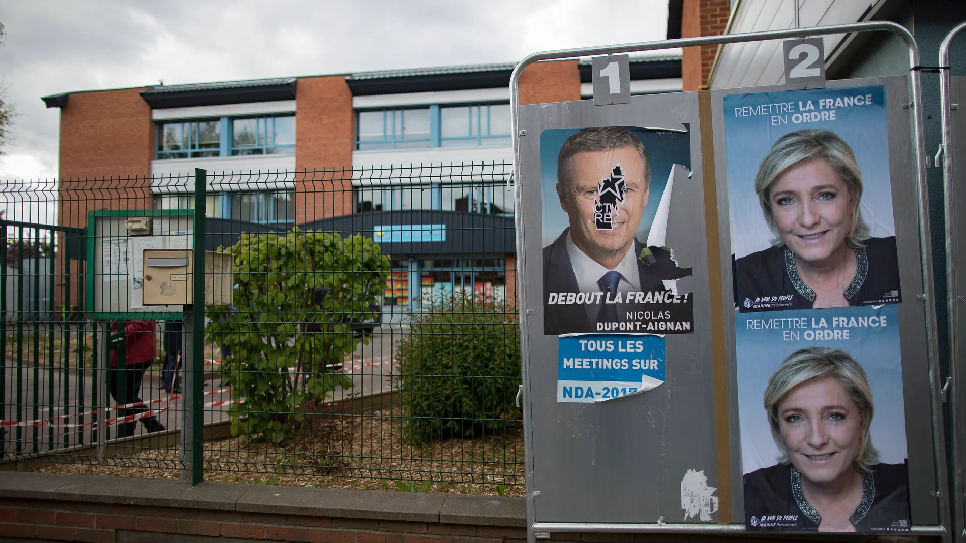 Carteles con alguno de los candidatos presidenciales en Francia adornan vallas publicitarias en el exterior de una mesa electoral en París (Francia)