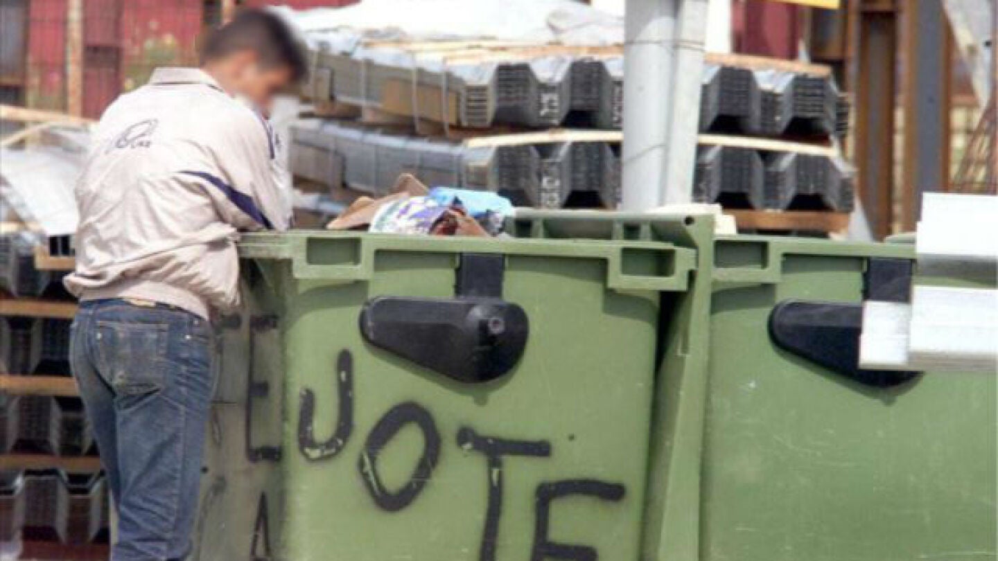 Un hombre buscando comida en un contenedor