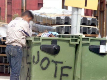 Un hombre buscando comida en un contenedor Un hombre buscando comida en un contenedor