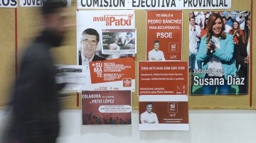 Un hombre pasa por delante de los carteles de apoyo a los tres candidatos a la Secretaría General del PSOE