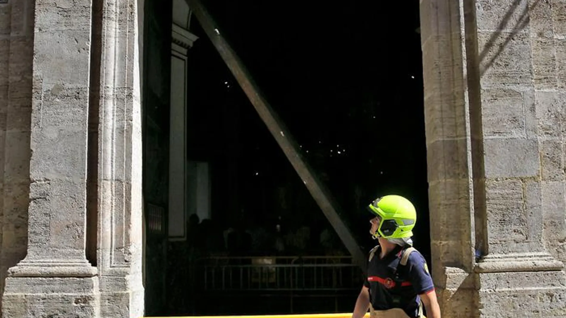 Un bombero observa la puerta de la Basílica de Valencia que se ha descolgado