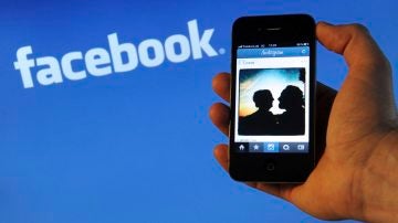 Un iPhone 4 frente al logo de Facebook en un ordenador