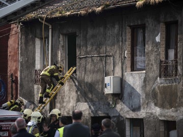 Imagen de archivo de los bomberos trabajando en una casa incendiada Imagen de archivo de los bomberos trabajando en una casa incendiada