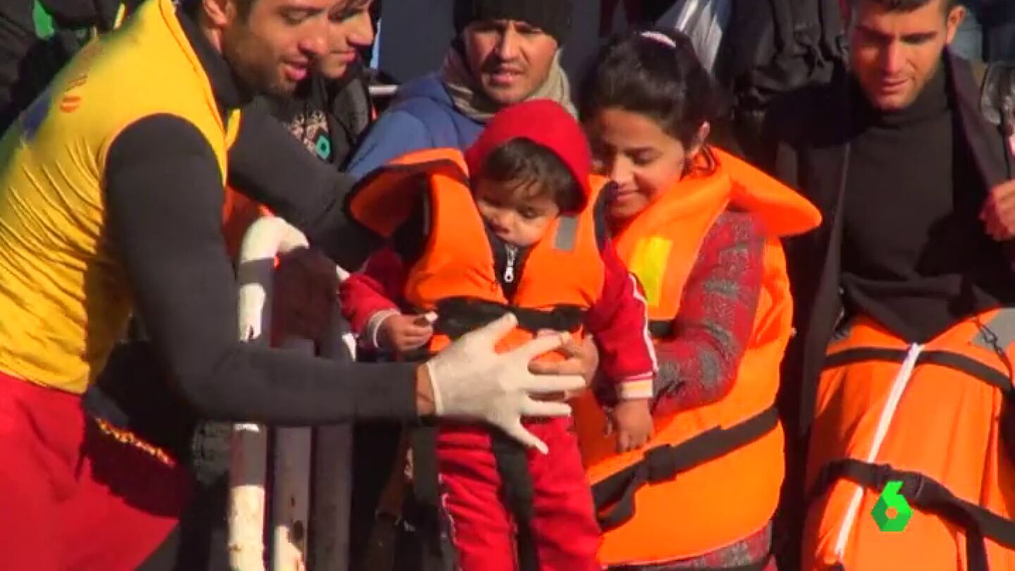 Un voluntario ayuda a un grupo de refugiados a llegar a tierra