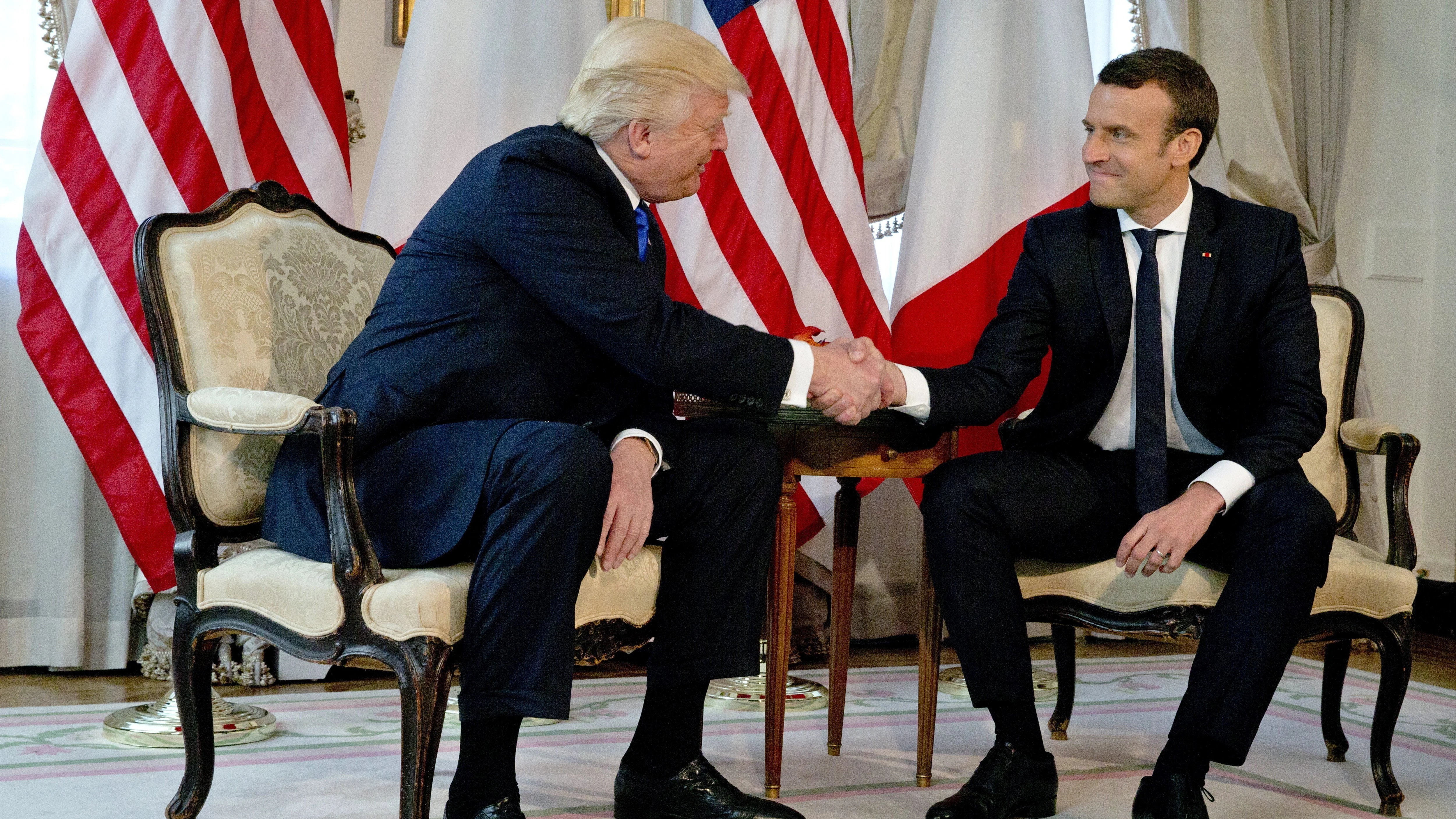 El presidente estadounidense, Donald Trump, estrecha la mano del presidente francés, Emmanuel Macron, durante su reunión en el marco de la cumbre de líderes de países de la OTAN