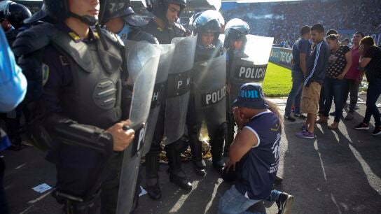 Un aficionado se arrodilla ante la polic&iacute;a en Honduras