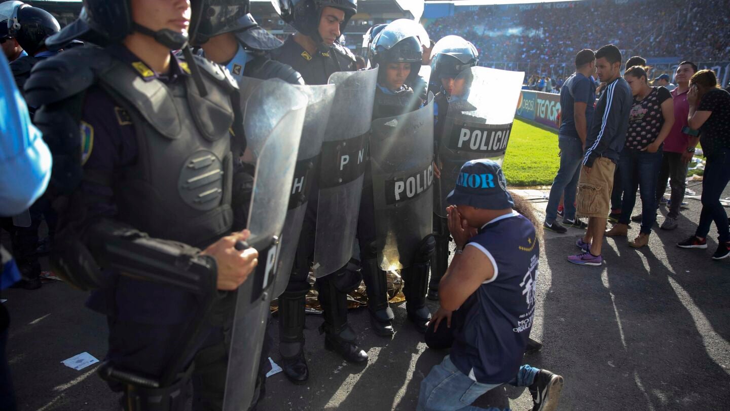 Un aficionado se arrodilla ante la polic&iacute;a en Honduras