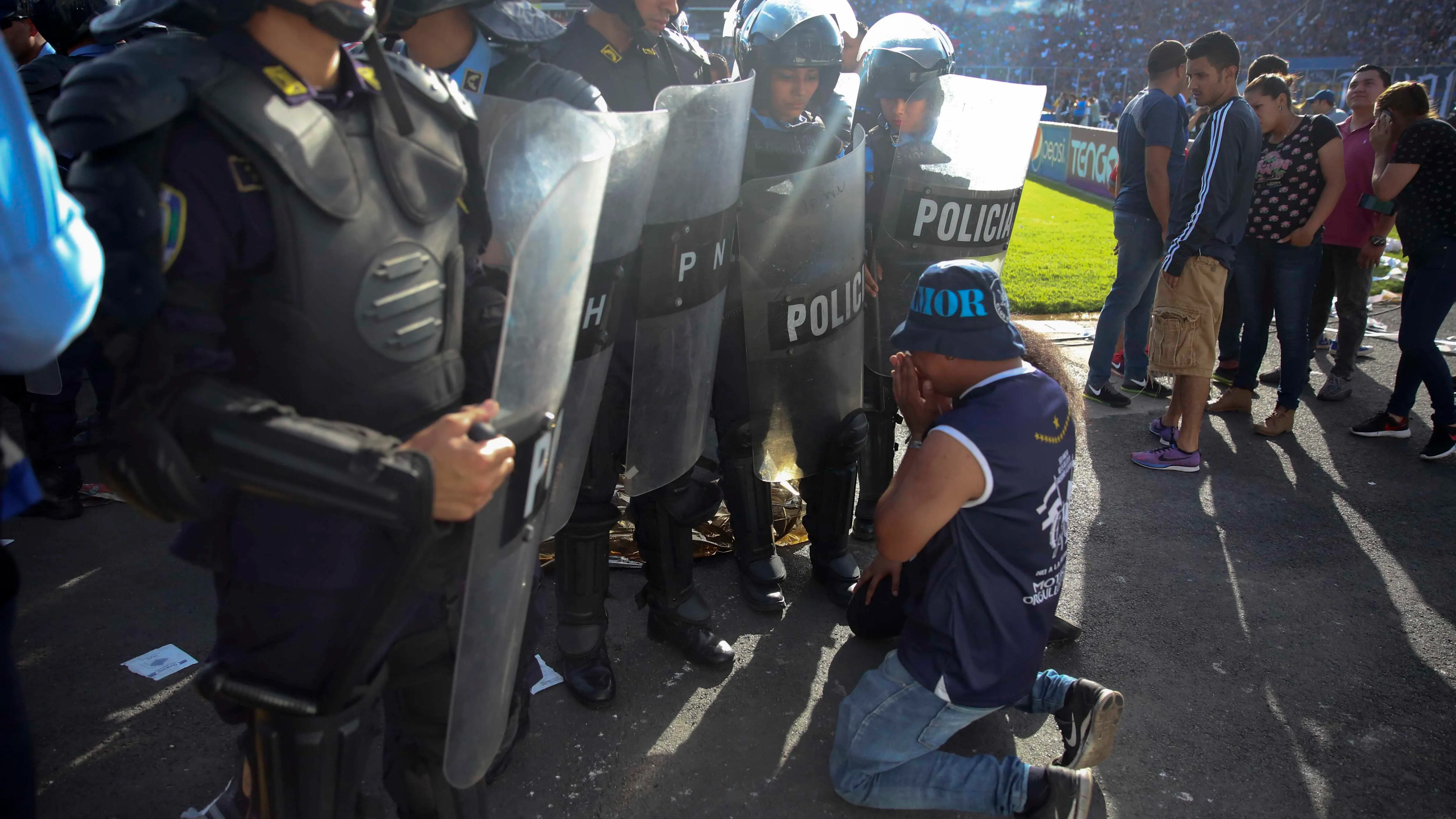 Un aficionado se arrodilla ante la policía en Honduras