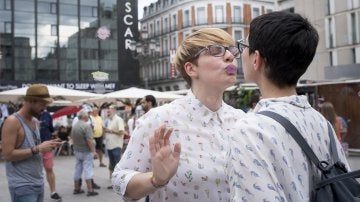 Una pareja se besa en el 'Muro de los besos perdidos' instalado en la plaza de Pedro Zerolo