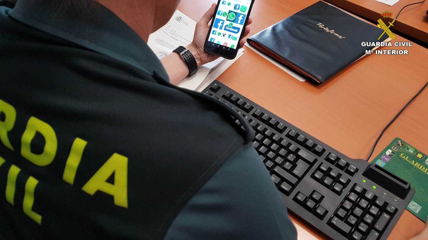 Un agente de la Guardica Civil con un tel&eacute;fono m&oacute;vil con acceso a redes sociales