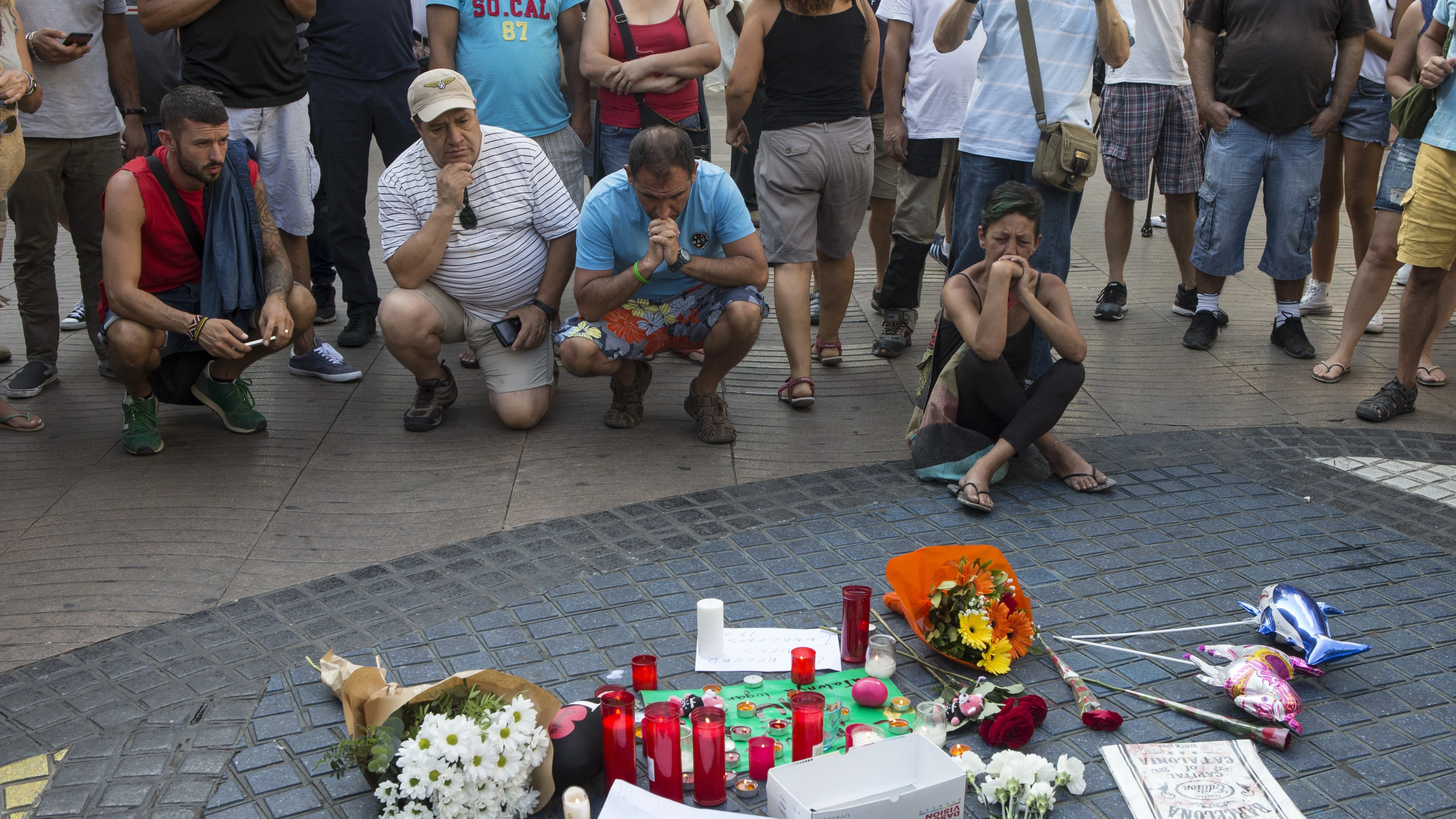 Varias personas se paran frente al mosaico de Miró en las Ramblas de Barcelona