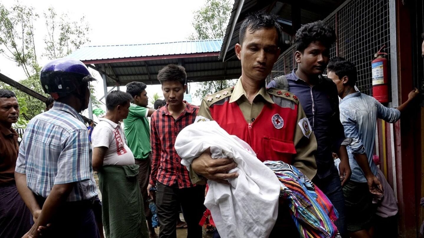 Un voluntario de la Cruz Roja lleva a un ni&ntilde;o junto con mujeres desplazadas rohingyas del &aacute;rea de Maungdaw, ayer. 