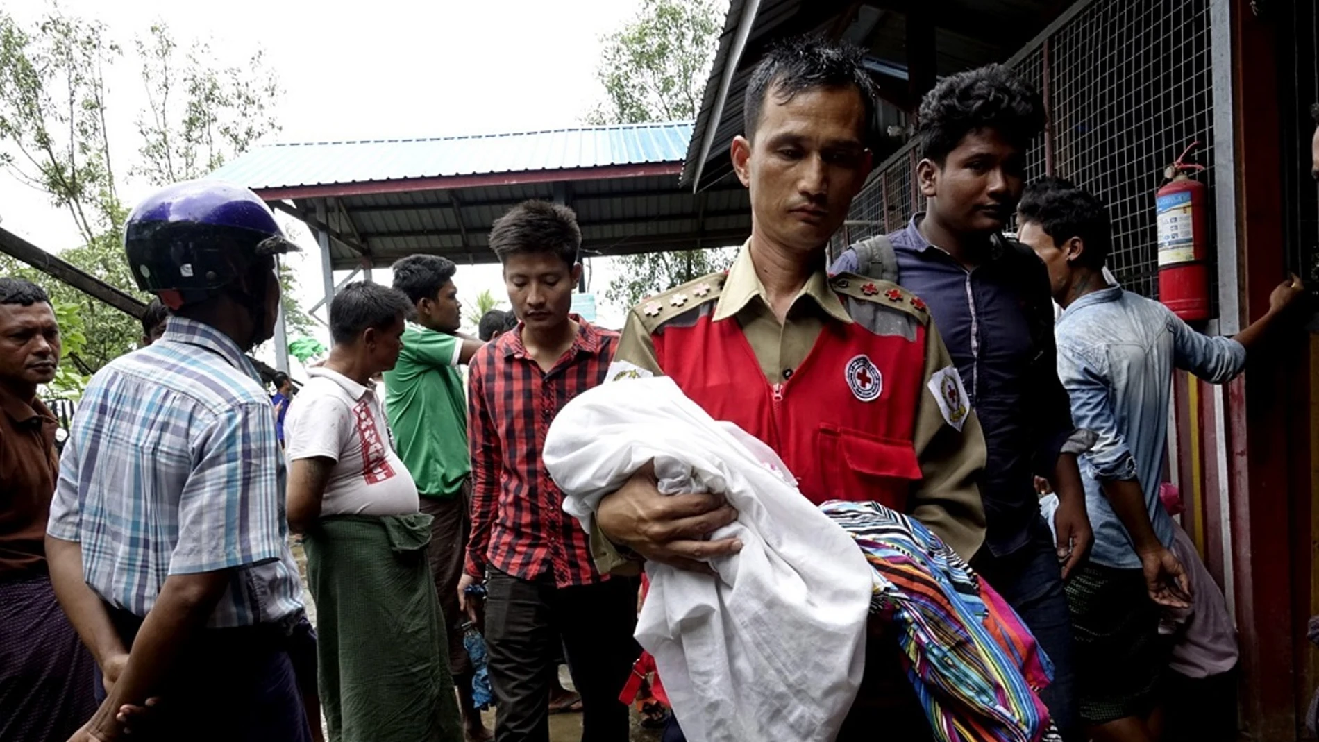 Un voluntario de la Cruz Roja lleva a un niño junto con mujeres desplazadas rohingyas del área de Maungdaw, ayer. 