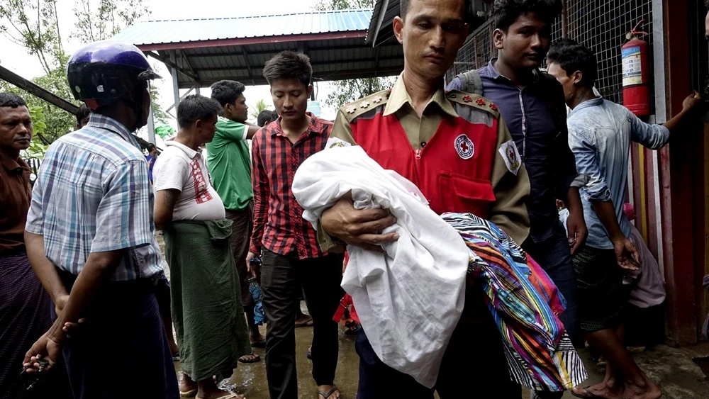 Un voluntario de la Cruz Roja lleva a un niño junto con mujeres desplazadas rohingyas del área de Maungdaw, ayer. 