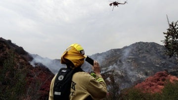 Un bombero y un helicóptero trabajan en las labores de extinción de el incendio de Los Ángeles