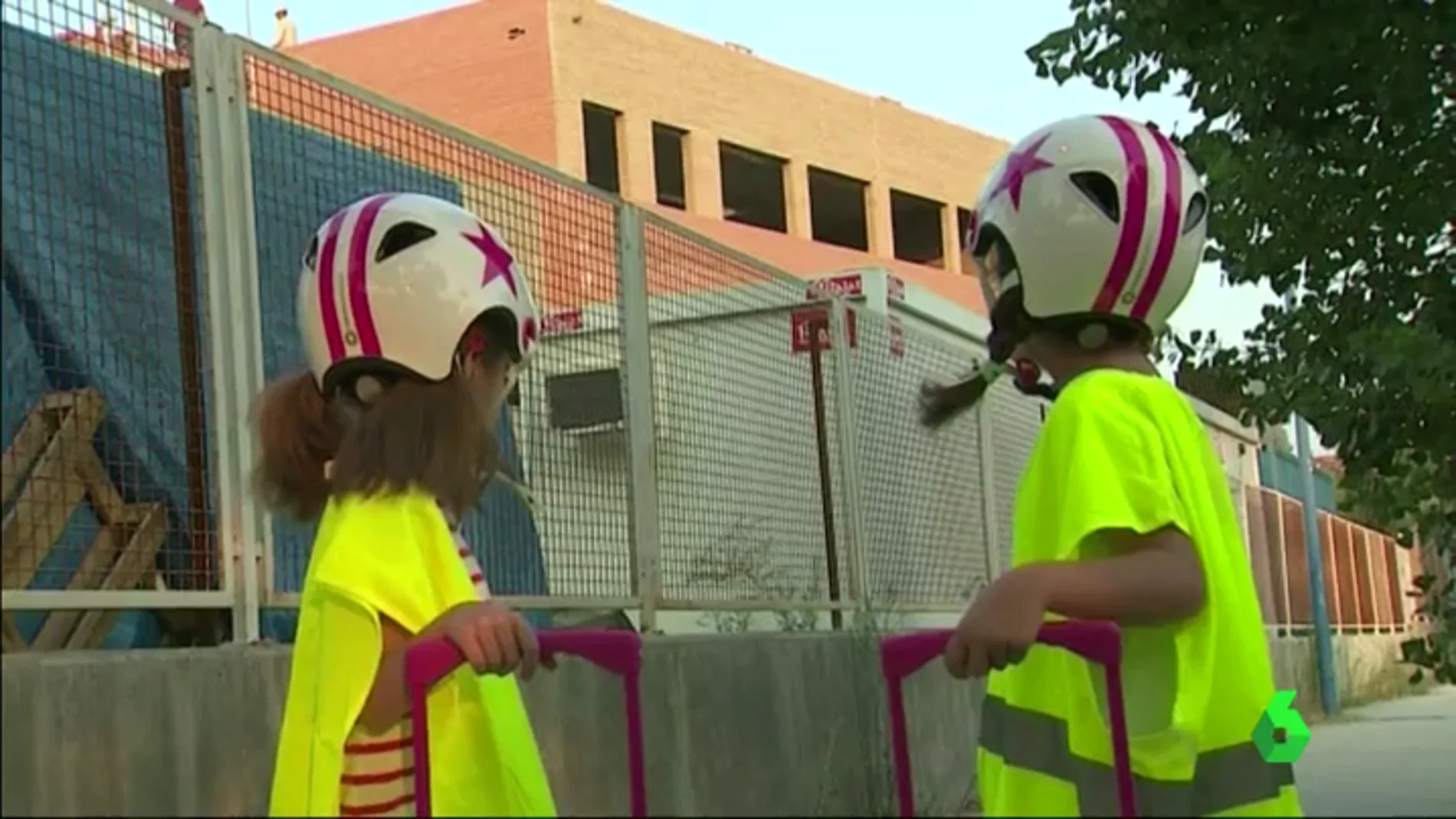 Dos niños asistiendo a su colegio en obras con casco y chaleco