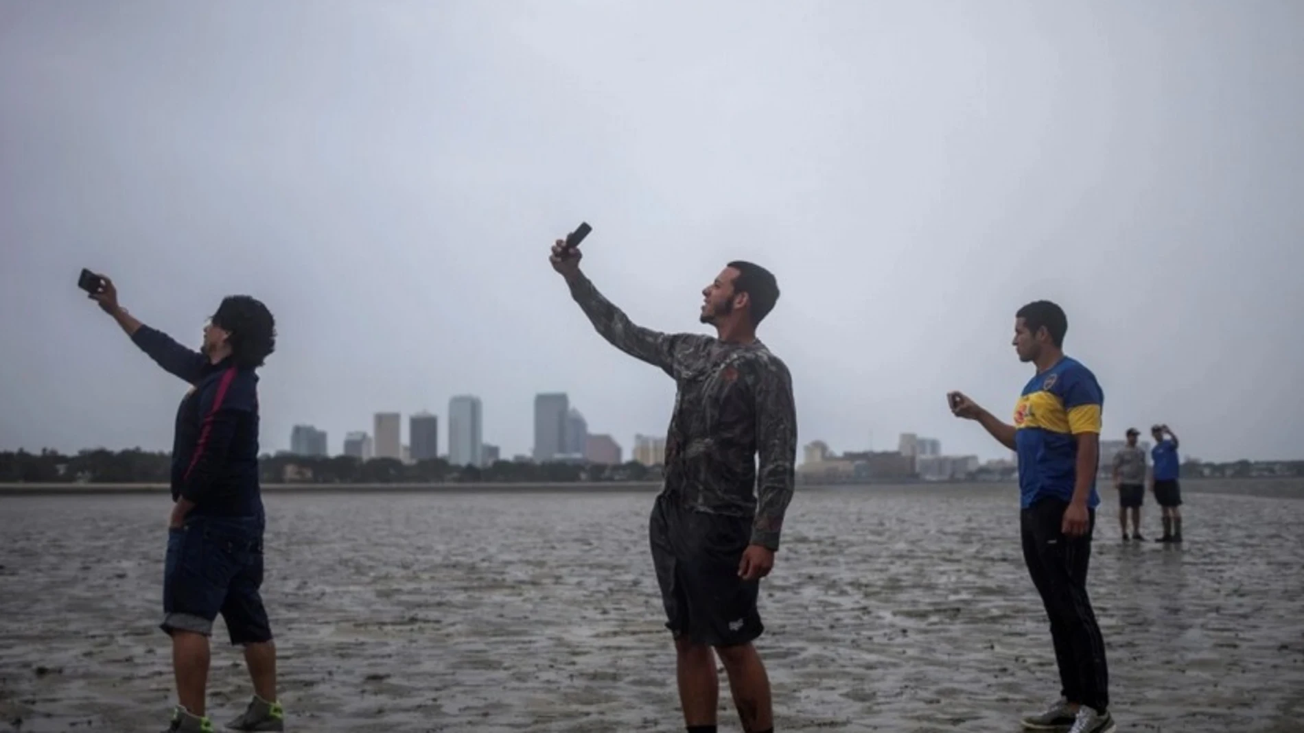 Varias personas se hacen selfies en la costa con el mar retirado